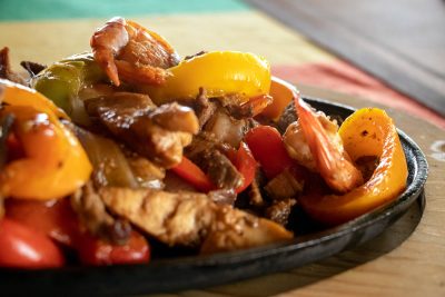 "A hot platter of traditional Mexican chicken fajitas with grilled bell peppers and onions, served beachside at Magdalena Bay."