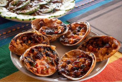 "Baked Chocolata clams au gratin with melted cheese, served as a gourmet signature dish at the hotel restaurant in Magdalena Bay."