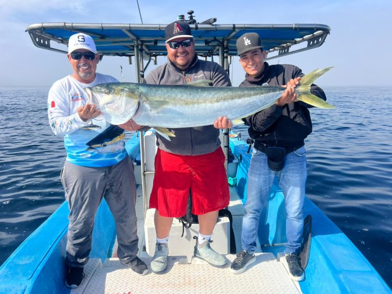 Three sport fishermen holding a giant amberjack during a fishing trip in the Pacific Ocean near Bahía Magdalena